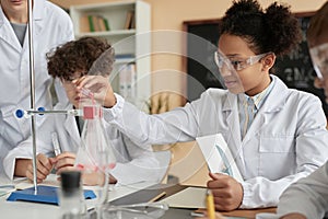 Side view smiling black schoolgirl doing science experiment in school