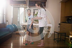 Side view of smiling boy looking at female therapist while standing on stress balls
