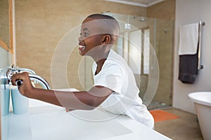 Side view of smiling boy with toothbrush looking at mirror