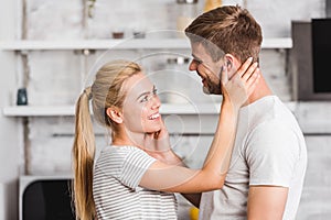 side view of smiling couple hugging in kitchen
