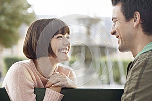 Side View Of Smiling Couple On Park Bench