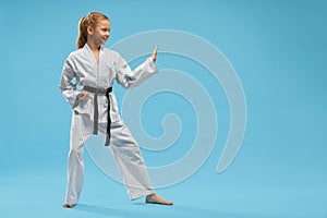 Side view of smiling girl in white kimono training karate