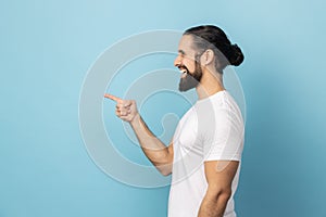 Side view of smiling man pointing finger aside, showing copy space for commercial text.