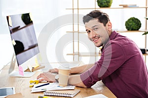 side view of smiling marketing manager working on computer at workplace