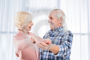 side view of smiling senior couple dancing together