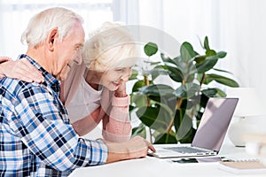 side view of smiling senior couple using laptop together