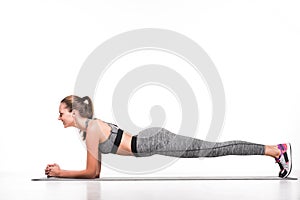 side view of smiling sportswoman doing plank exercise on yoga mat