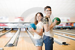 Teenage Couple With Balls Standing In Bowling Club