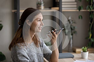 Side view smiling woman recording audio message on smartphone