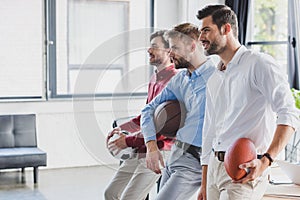 side view of smiling young businessmen holding balls and looking away