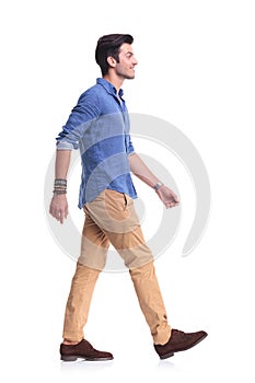 Side view of a smiling young casual man walking