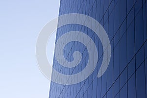 Side view of a smooth blue glass window wall of an office building.