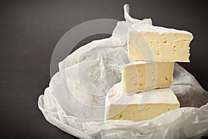 Side view of Soft French Brie cheese cuts served on parchment paper