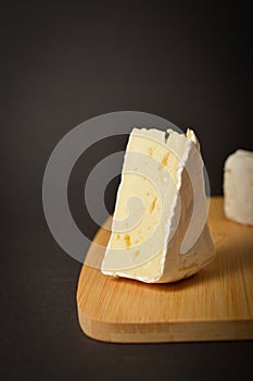 Side view of Soft French Brie cheese cuts served on wooden board