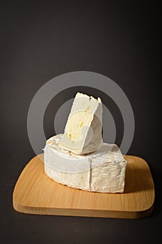 Side view of Soft French Brie cheese cuts served on wooden board