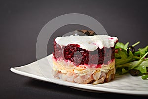 Side view of Soviet layered fish salad Herring under fur coat. Portion with marinated herring, onion, grated potato, beetroot,