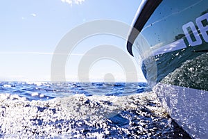 Side view Speeding fishing motor boat with drops of water. Blue ocean sea water wave reflections with fast fishing yacht. Motor bo