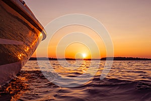 Side view Speeding fishing motor boat with drops of water. Blue ocean sea water wave reflections at the sunset. Motor boat in the