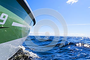 Side view Speeding fishing motor boat with drops of water. Blue ocean sea water wave reflections at the sunset. Motor boat in the