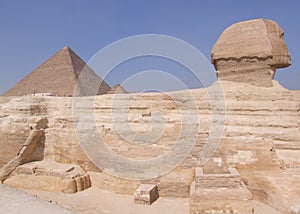 Side view of the of the Sphinx statue Giza Egypt with the Great Pyramid in the background.