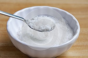 Side view of a spoon filled with coarse salt with customizable space for text or ideas.