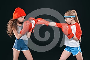 Side view of sportive girls pretending boxing isolated on black