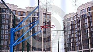 Side view sports ground basketball hoop with net in residential house yard. No people on cloudy winter day in urban city