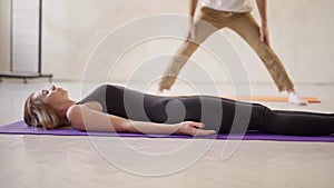 Side view sporty relaxed woman practicing yoga in yoga class, lying in resting pose Savasana or Dead Body exercise in