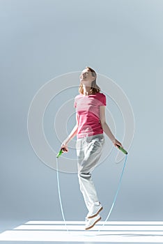 Side view of sporty woman exercising with skipping rope