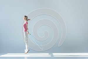 Side view of sporty woman exercising with skipping rope