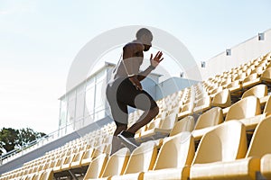 Side view of a sporty young man runner on stadium