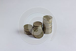 Side view of stacks of coins increasing in height, on white studio background