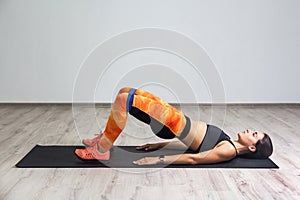 Side view of strong and fit athletic young caucasian woman in sportswear with bands training legs and glutes muscular. Fitness