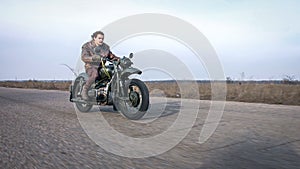 Side view of a stylish cool man in leather jacket driving vintage motorcycle