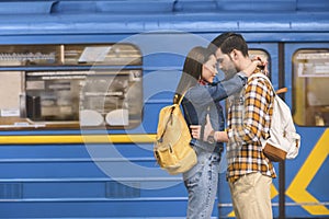 side view of stylish couple of tourists embracing each other at subway