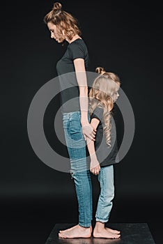 Side view of stylish daughter and mother standing back to back