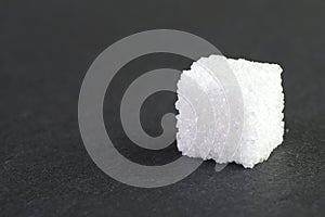 Side view of a sugar cube on a gray background.