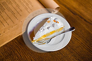 The side view of the tasty fruit cake decorated with fresh cream and fruit placed on the craft menu on the wooden table.