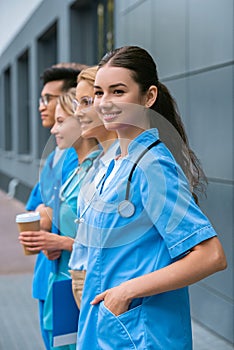 side view of teacher and happy multicultural students standing in row