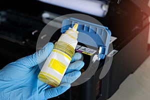 Side view of technician filling printer with ink