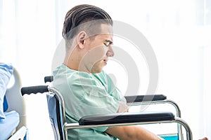 Side view, Teenage caucasian Male patient having stressed while sitting on wheelchair in hospital room