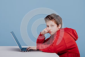 Side view of thoughtful schoolboy in red sweatshirt