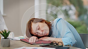 Side view tired mature woman sighing taking a nap sitting at table in office. Portrait of sad exhausted Caucasian