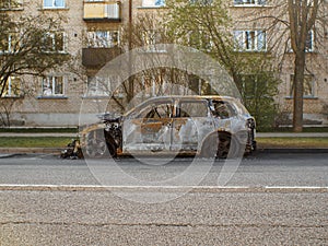 Side view to the burned car on the street during the day on district environment. Selective focus on vehicle.