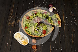 Side view of traditional Italian pizza with ingredients: spanish onions, piece of cheese, olives, tomatoes and sea salt