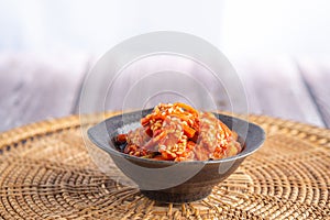 Side view of traditional Korean dishes Kimchi in a bowl on rattan handmade pacemat. Space for text. Concept of Korean foods