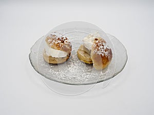 Side view of traditional Swedish semla, or fastlagsbulle, with whipped cream, almond paste and confectioners\' sugar.