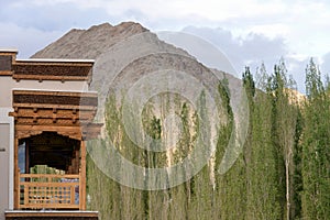 Side view of traditional wooden architecture of the house balcony with pine tree and mountain.