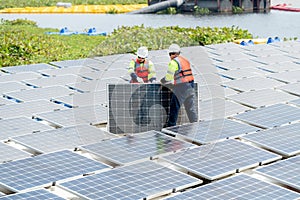 Side view of two Asian professional technician workers with safety uniform stand and help to check or maintenance solar cell