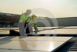 Side view of two Caucasian technician workers look at laptop to check and maintenance solar cell panels on rooftop of factory or